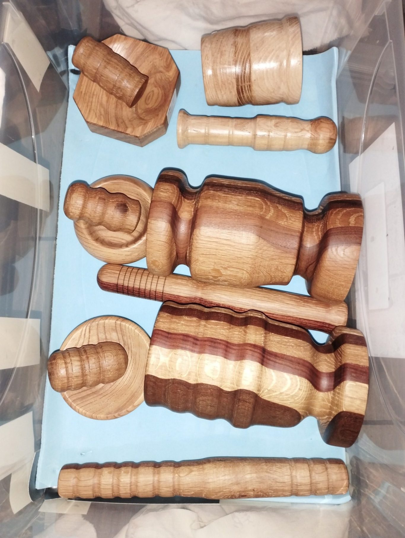 Ensemble de pièces en bois tourné, de différentes formes et tailles, sur fond bleu.
